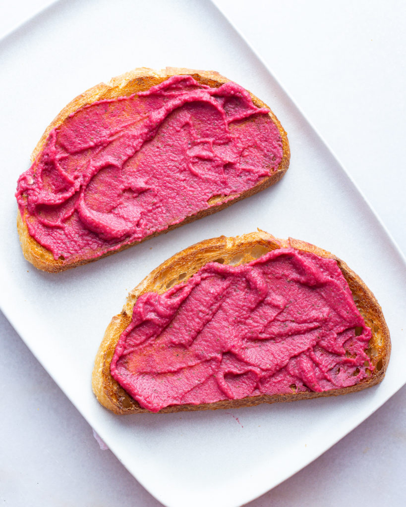 Beet hummus spread on toasted bread slices