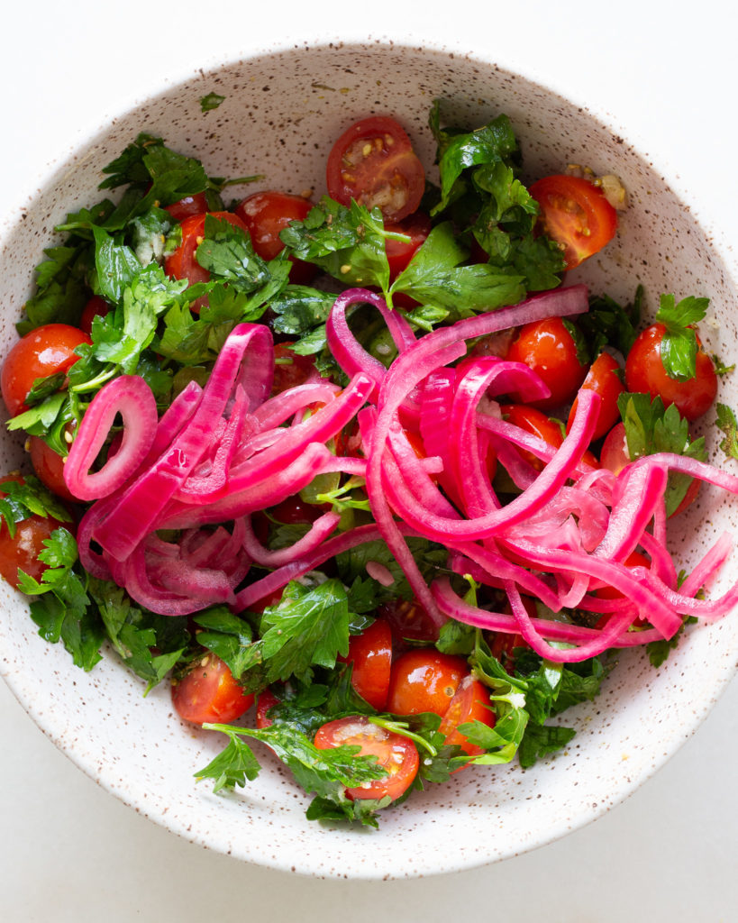 Pickled red onions added to bowl
