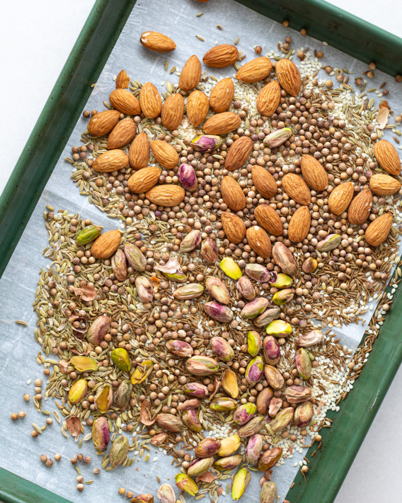 Almonds, pistachios and seasonings on baking sheet 