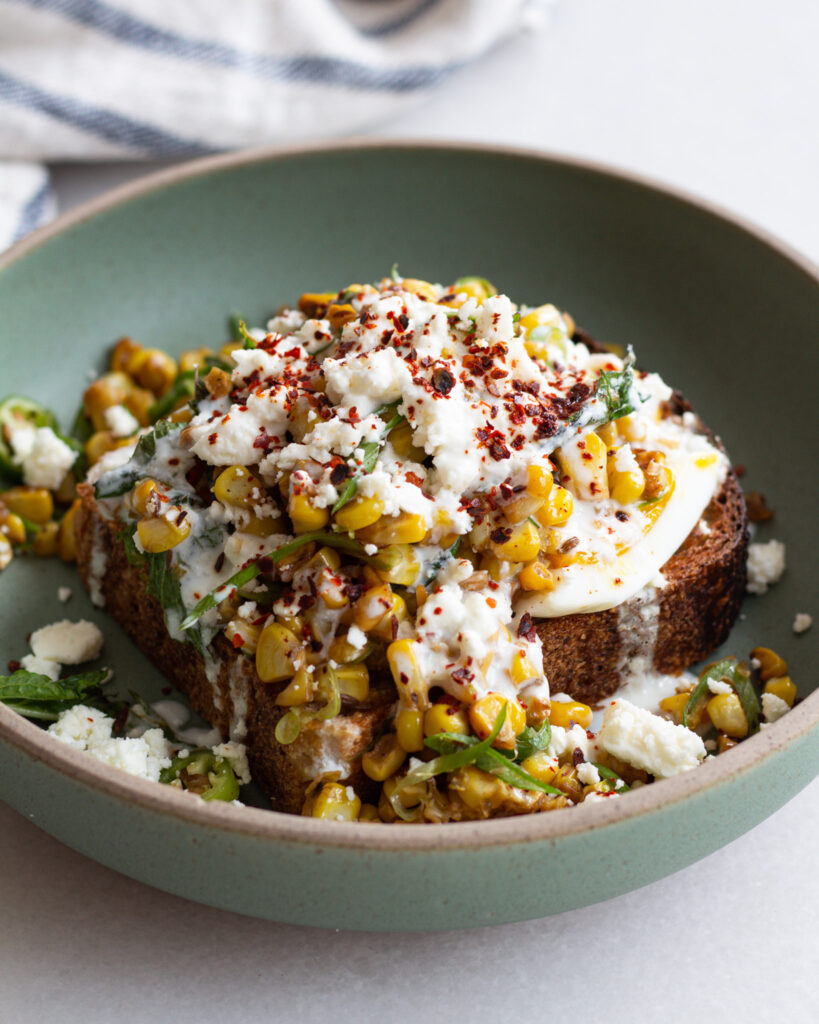 Finished cumin corn with garlic lime dressing over toast with soft boiled eggs