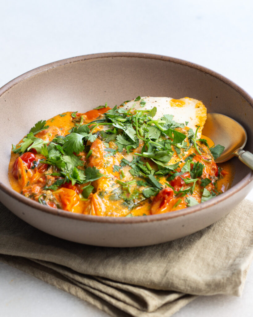 Finished tomato curry in bowl with spoon