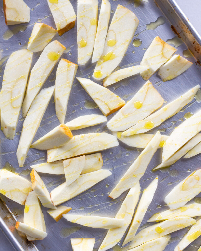 Sliced parsnips with olive oil on baking sheet