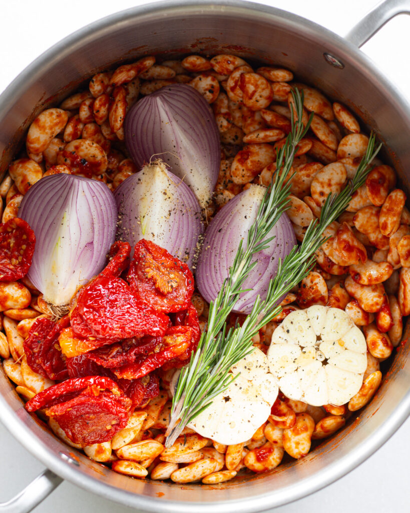 seasoned beans, onion, rosemary, tomatoes and garlic in pot