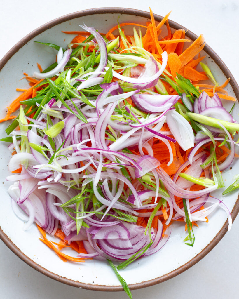the ingredients for the raw carrot salad in a bowl, but not mixed
