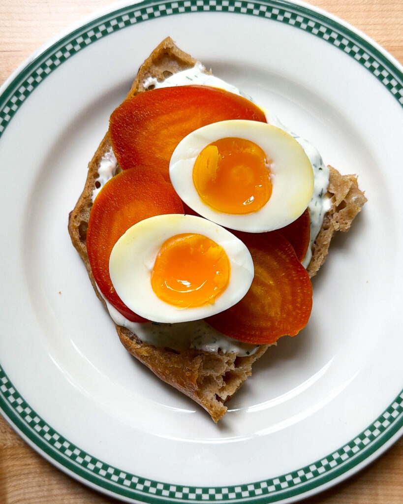 Jammy eggs on top of beets for a çilbir sandwich