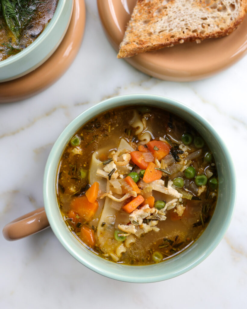 A large cup of vegetarian chicken noodles soup shows the tofu "chicken" and the vegetables and broth.