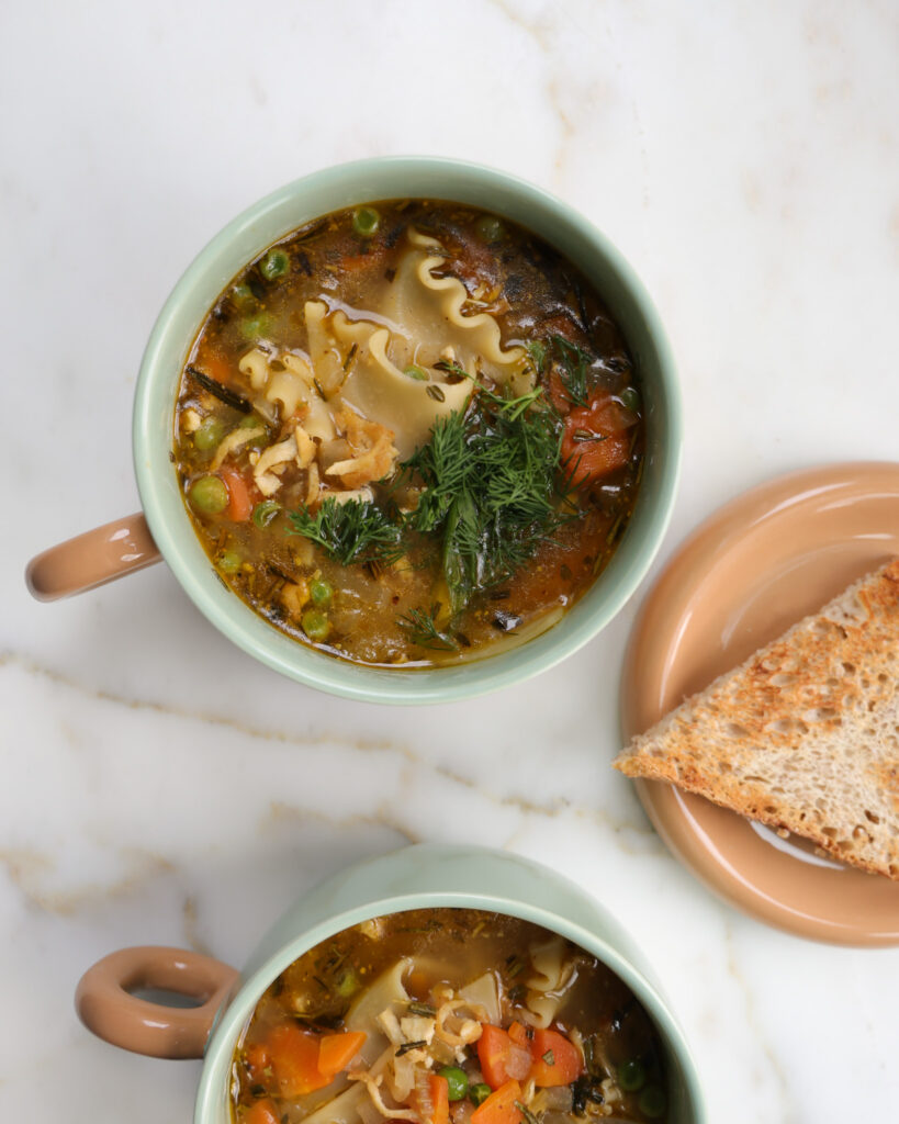 This image shows two vegetarian chicken noodle soups in soup mugs
