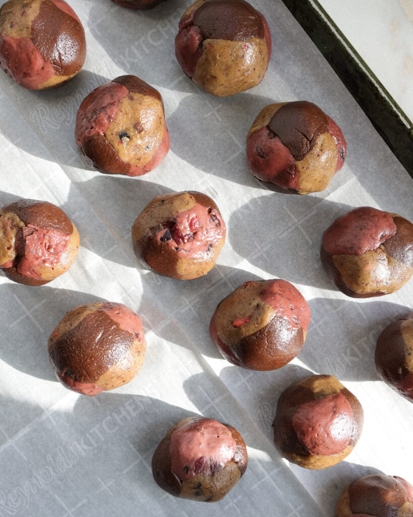 Rolled up cherry chocolate pretzel cookie dough balls on a baking sheet pan