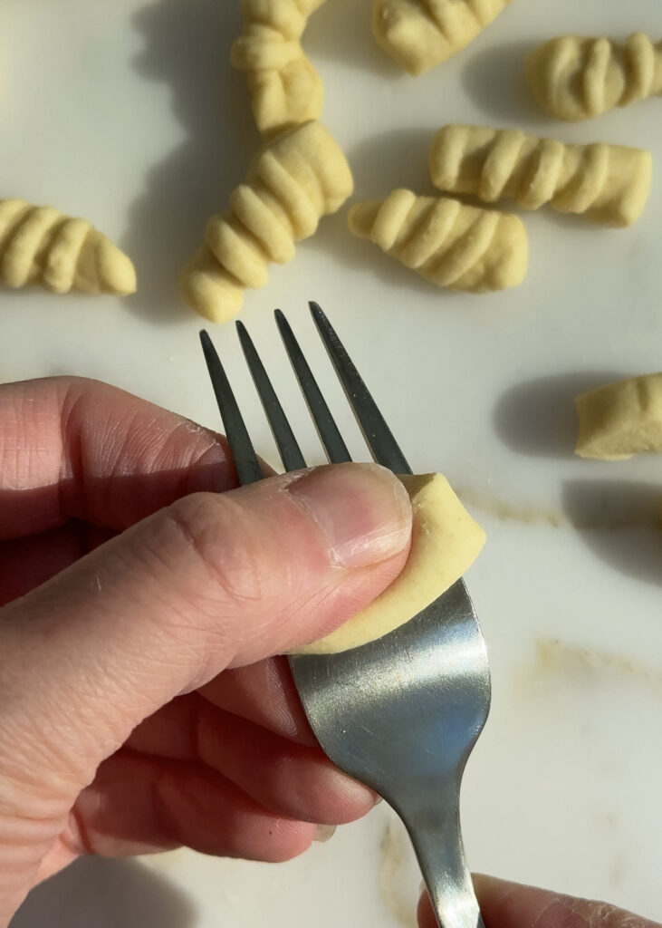 shaping homemade gripper shaped pasta with a fork.