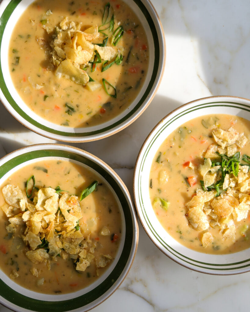 Three bowls of potato soup topped with salt and vinegar chips.