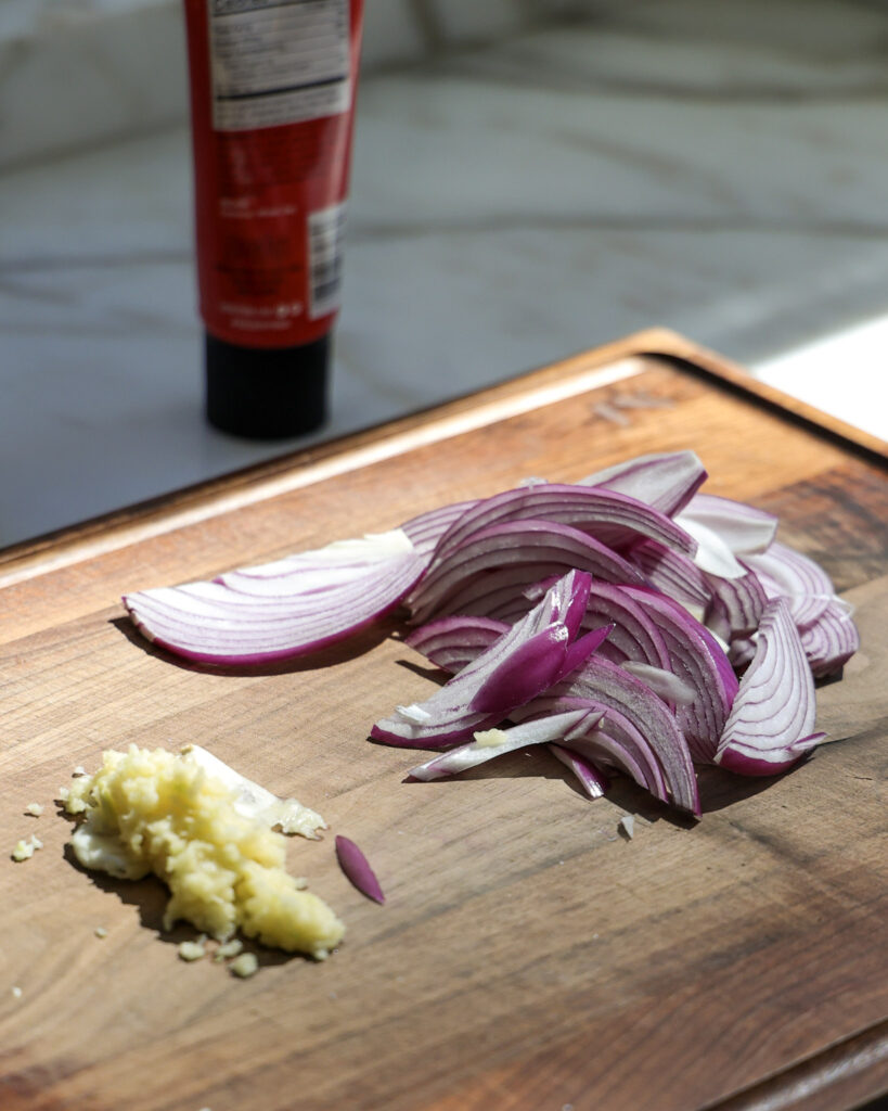 red onion and garlic on a cutting board.