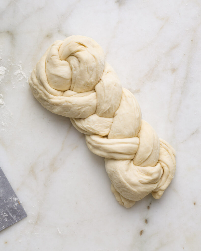 vegan brioche dough being shaped into a braided loaf.