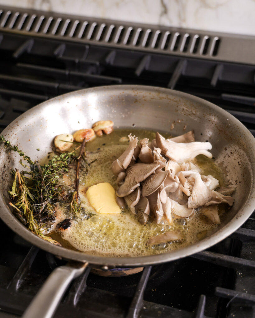 lions mane mushroom steaks in a saucepan with butter and herbs.