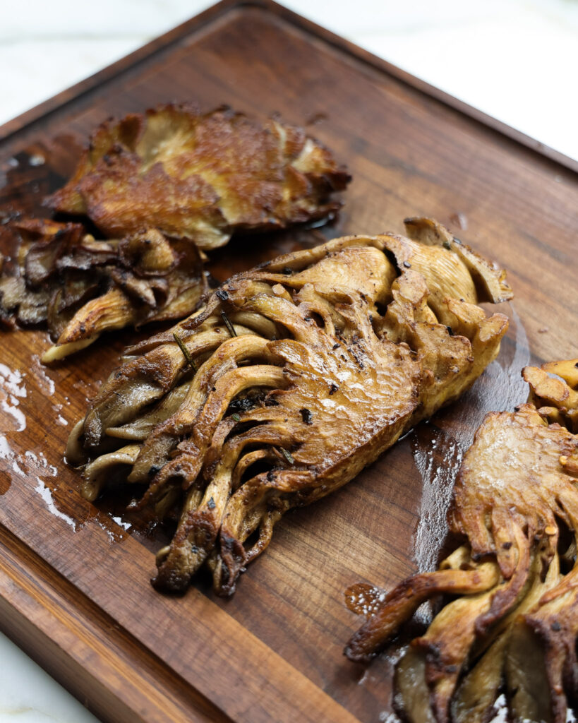 Pan seared mushroom steaks on a cutting board.
