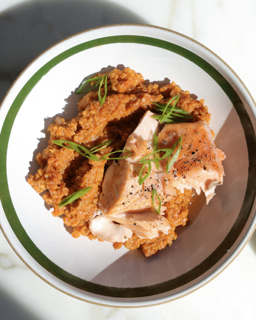 salmon over baked gochujang quinoa topped with scallions.
