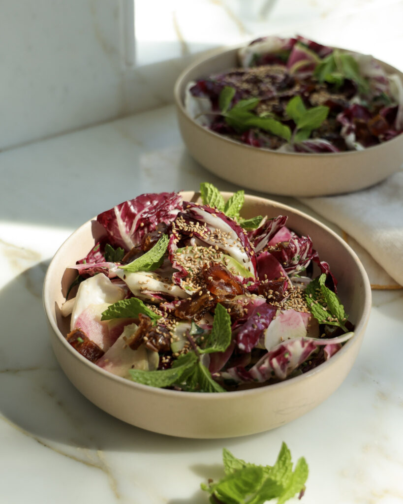 Lemon tahini salad topped with sesame seeds and mint in a bowl.