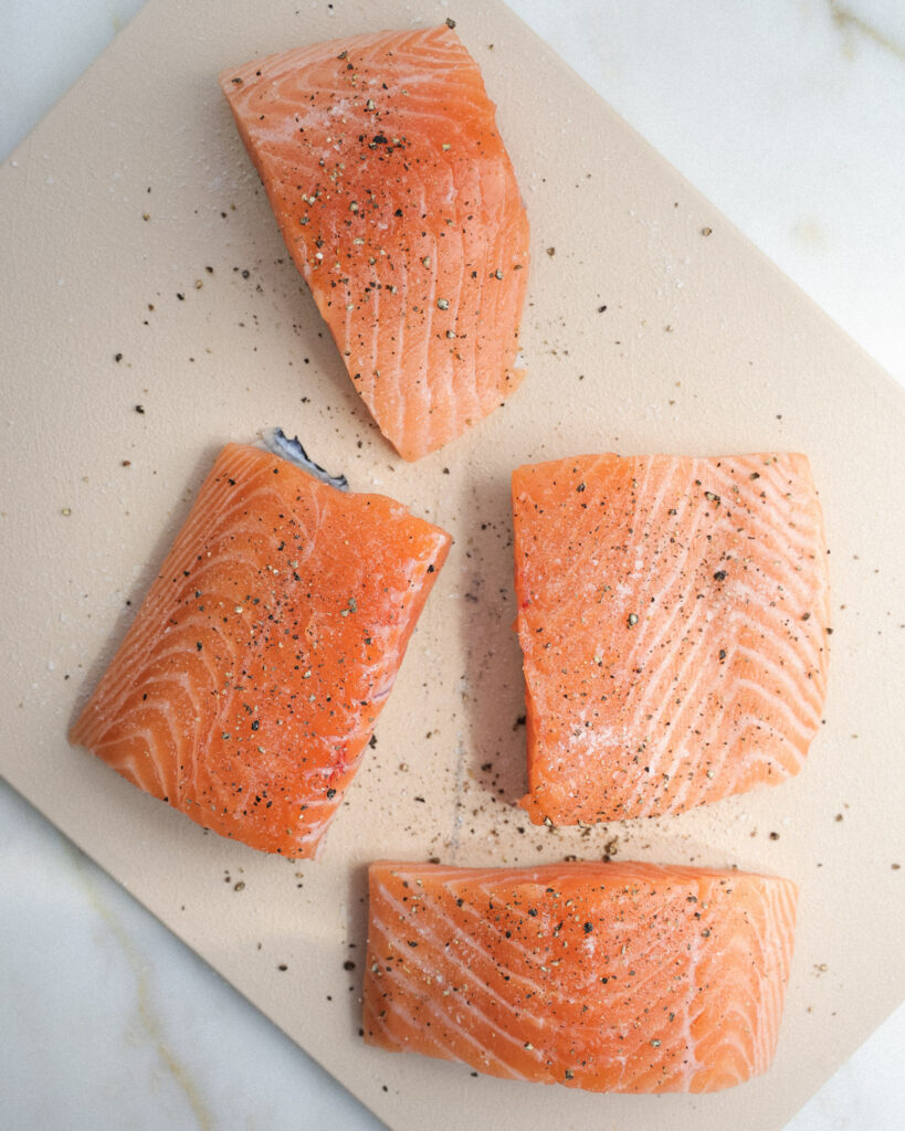 seasoned salmon filets on a cutting board.