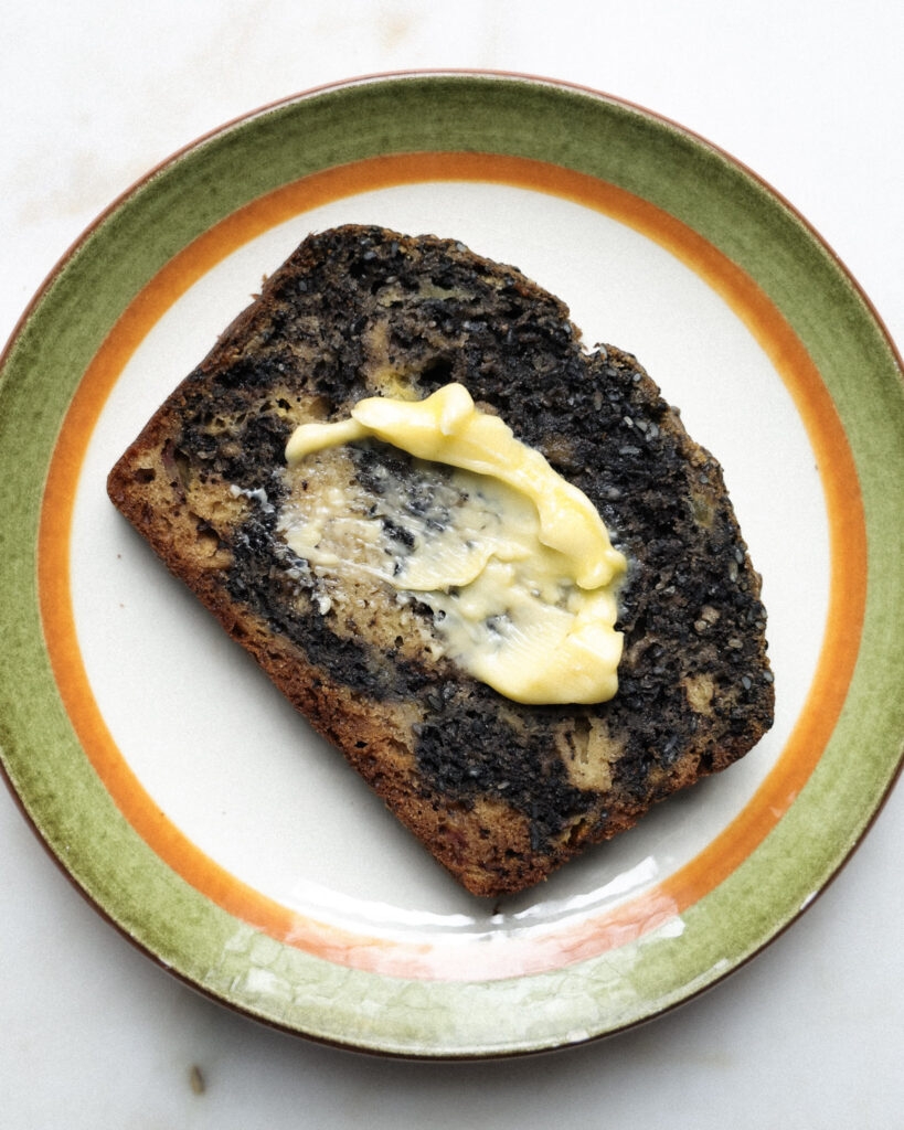 sliced black sesame banana bread on a plate topped with butter.