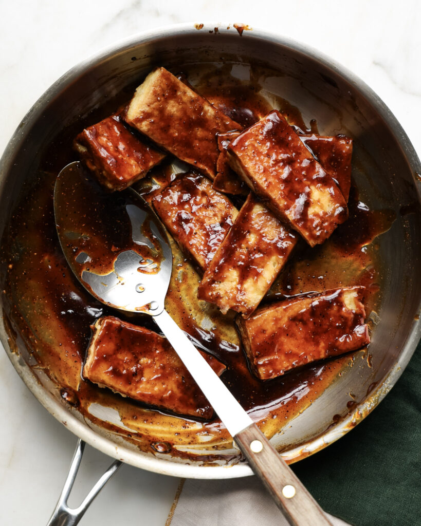 tofu chicken wings being tossed in a honey coriander sauce.
