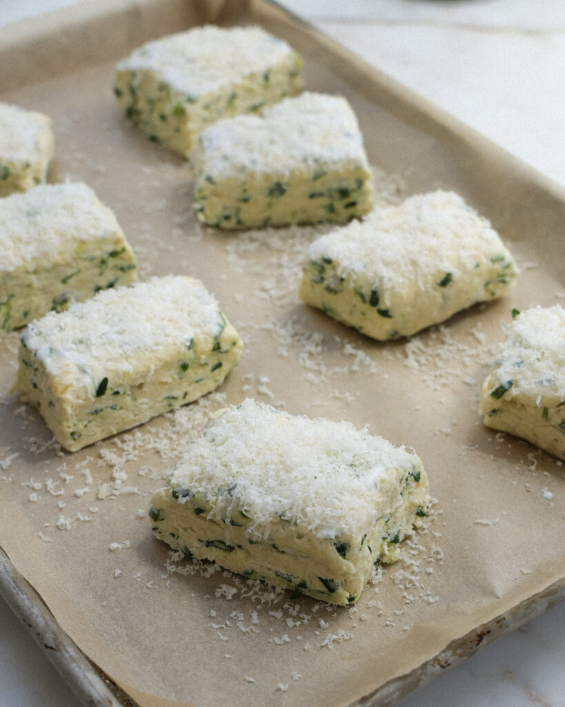 unbaked ramp biscuits on a baking sheet topped with parmesan cheese.