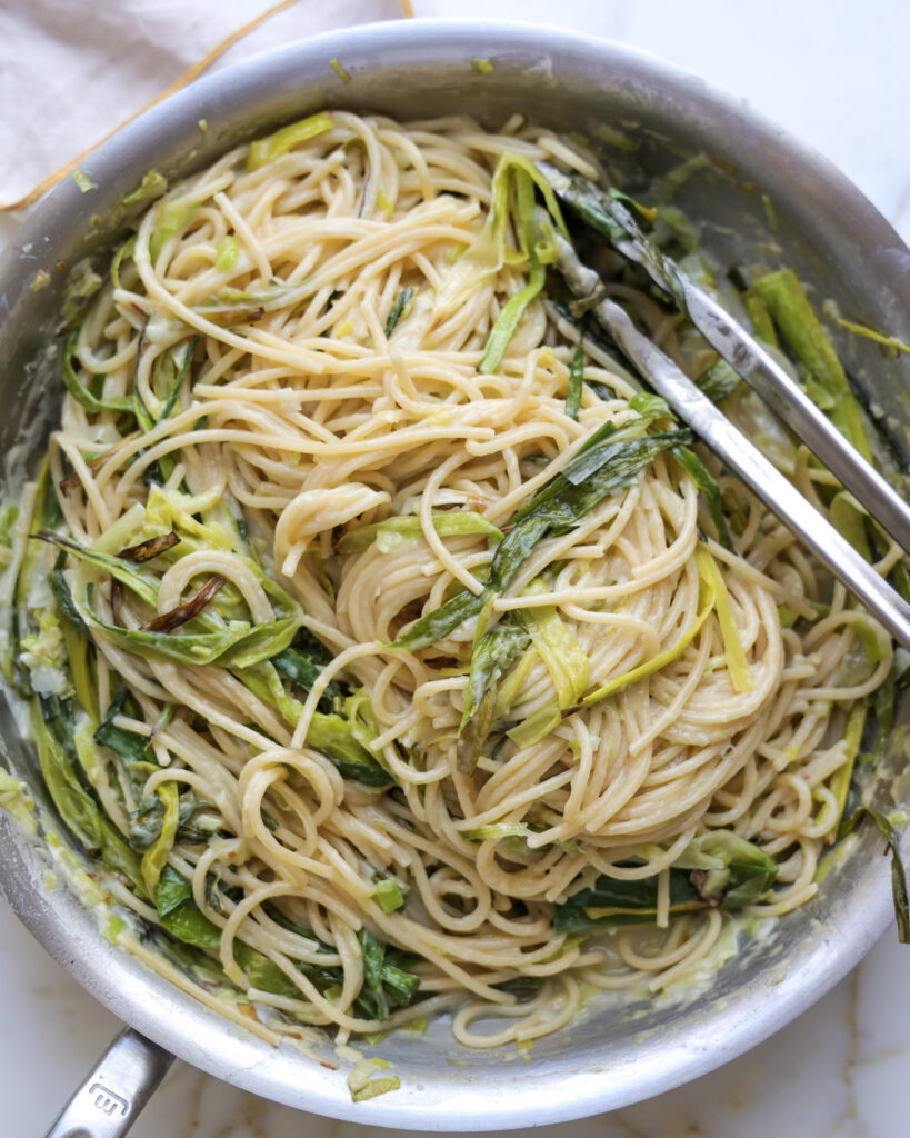pasta being tossed in a leek pasta sauce.