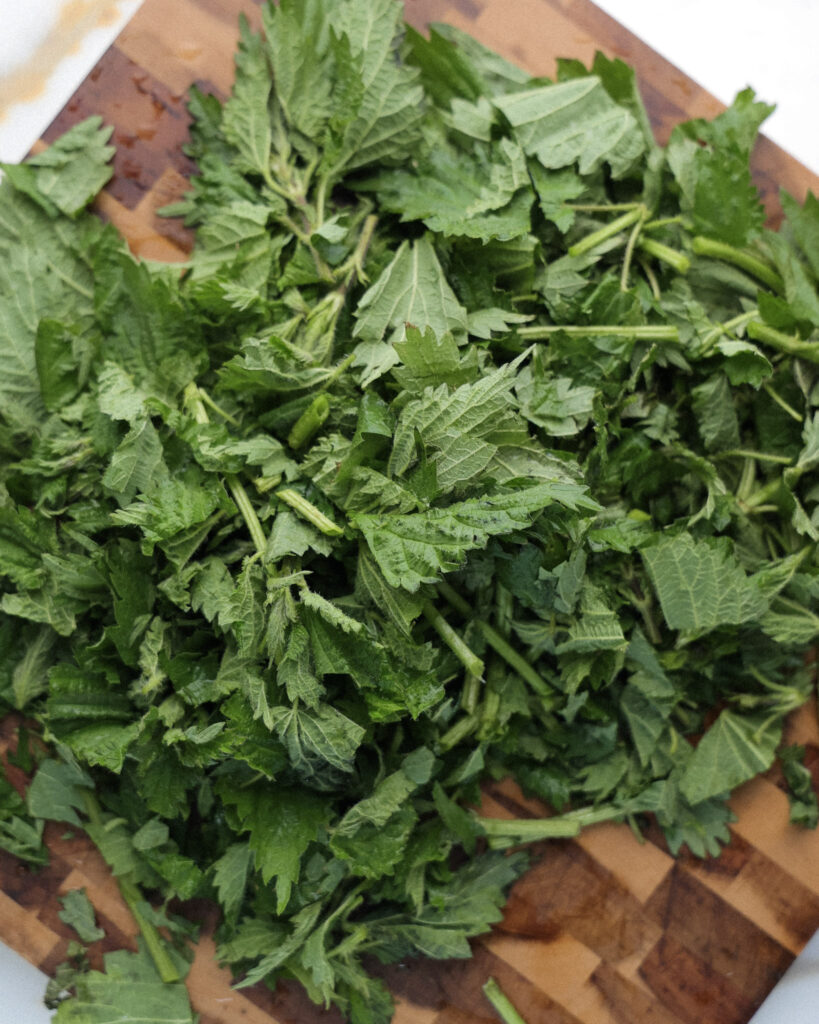 Stinging nettles chopped on a cutting board.