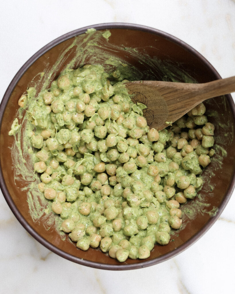 Chickpeas being tossed in a green cashew dressing.