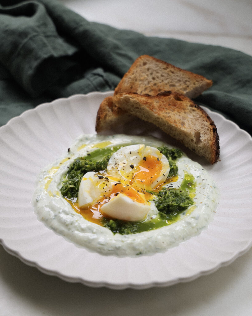 Soft boiled eggs over green sauce and skyr served with toast