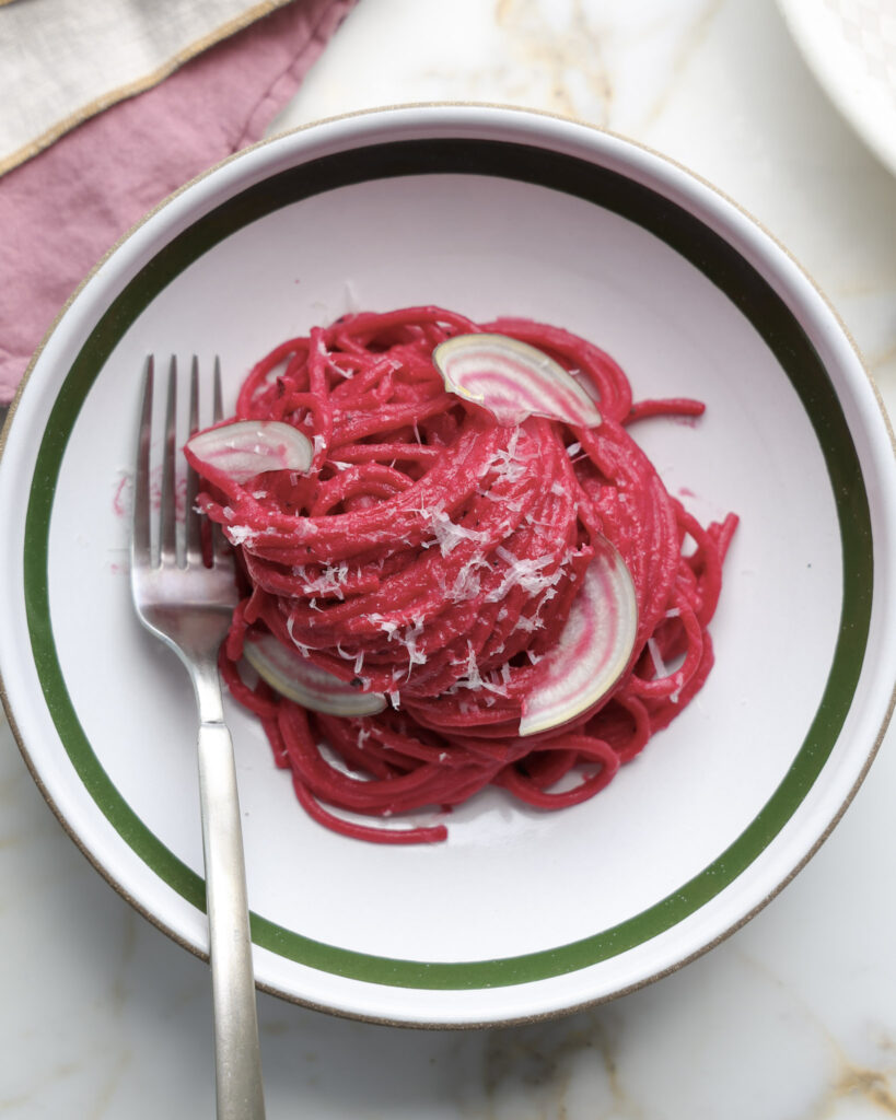 beet pasta with sliced radish on top.