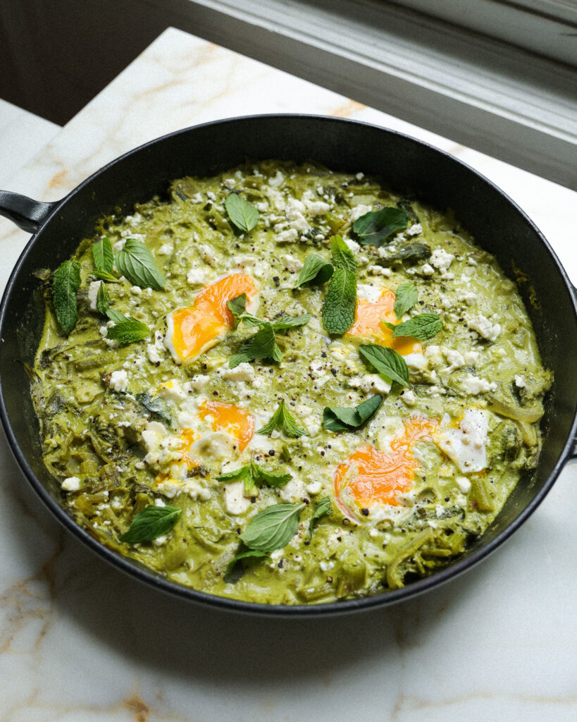 a pan of green shakshuka garnished with mint and feta