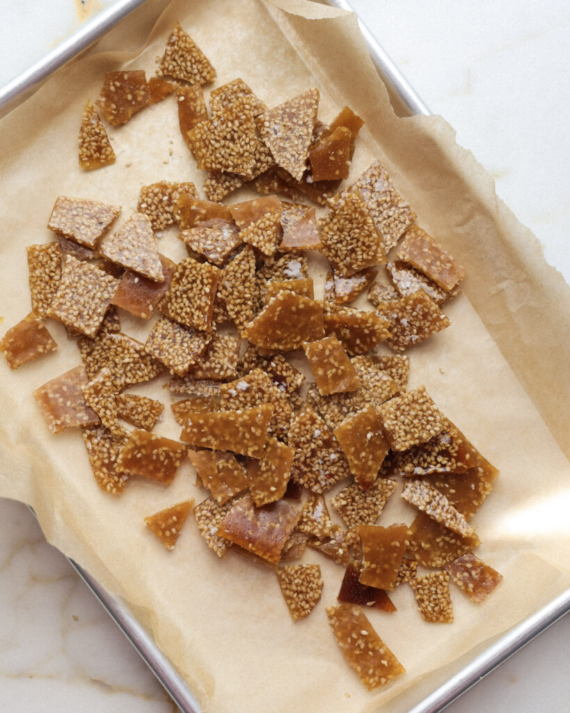 Broken up sesame bark on a baking sheet.
